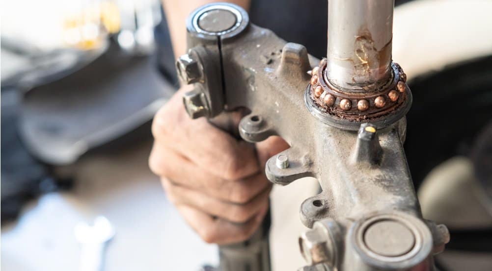 A close-up photo of worn-out motorcycle steering bearings that require maintenance.